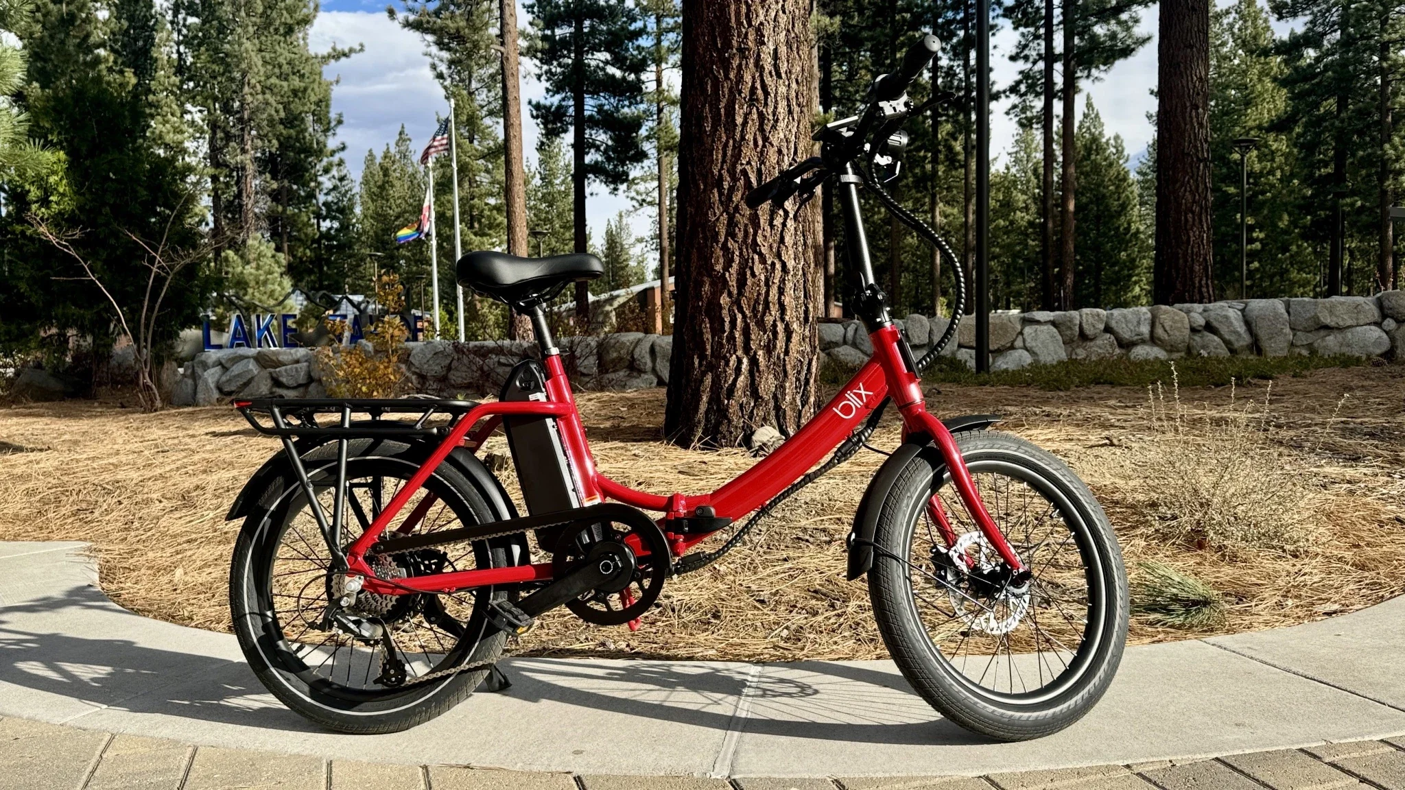 A Blix Vika X e-bike on a sidewalk surrounded by pine trees.