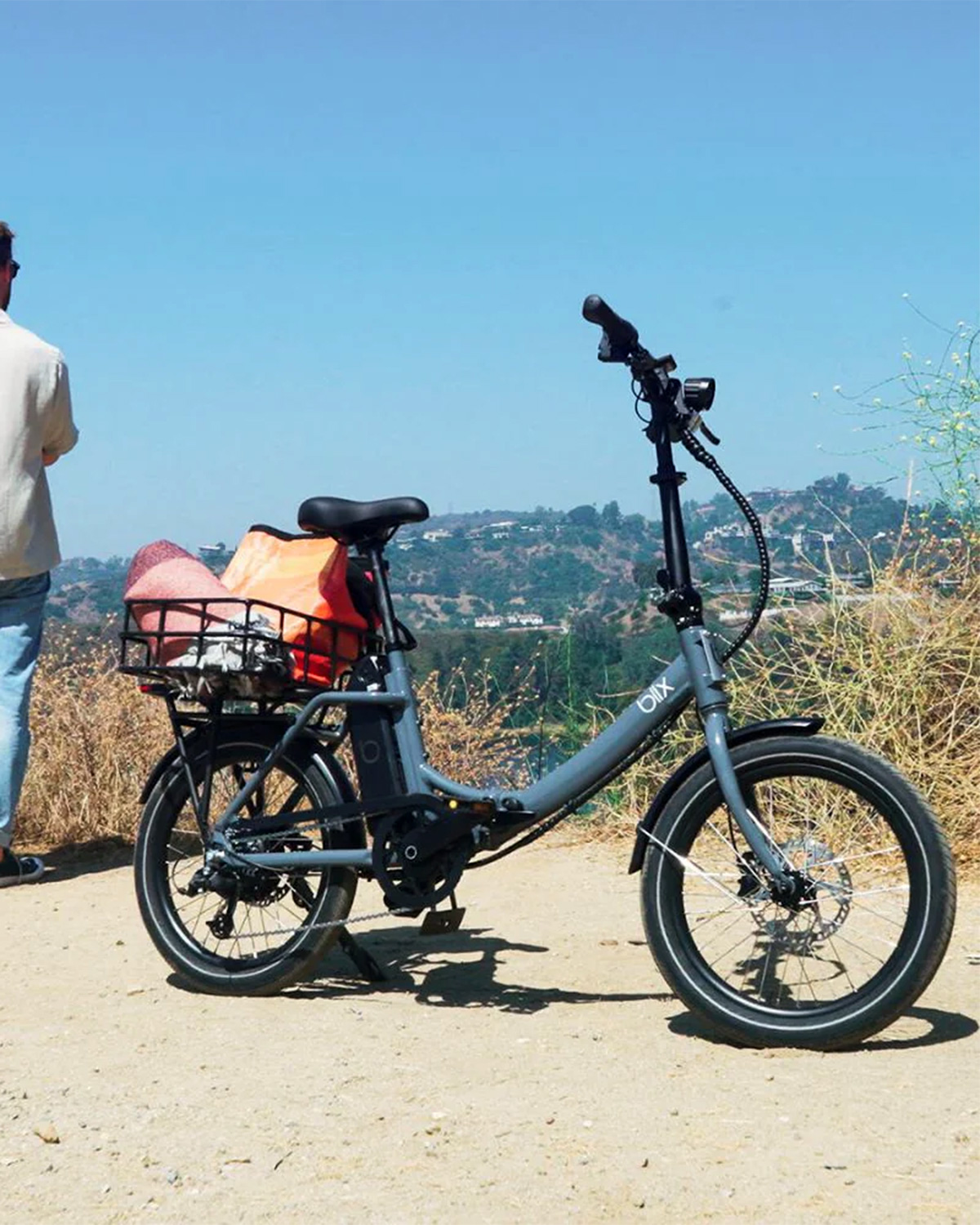 An e-bike parked at on overlook with water and foliage in the background.
